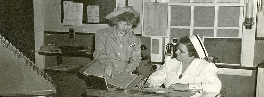 Ward clerk consulting charge nurse at Grasslands Hospital, ca. 1950 (P-552). 